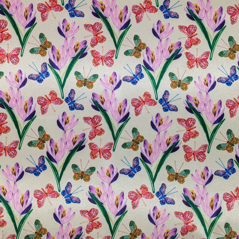 A close up of polyester silk fabric with a stunning print of blue, red and green butterflies fluttering around pink and purple flowers.
