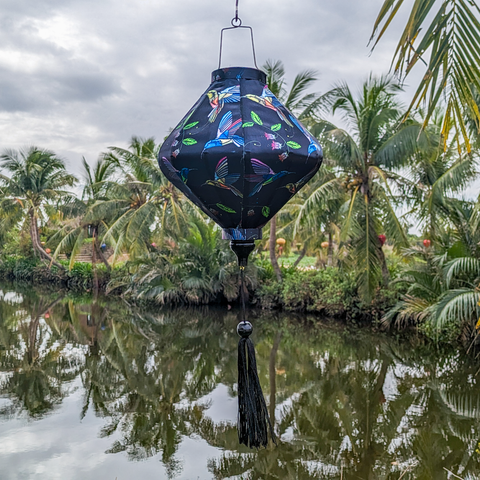 Lozenge shaped Vietnamese Hoi An lantern set against beautiful scenery, perfect for indoors or outdoor decor.