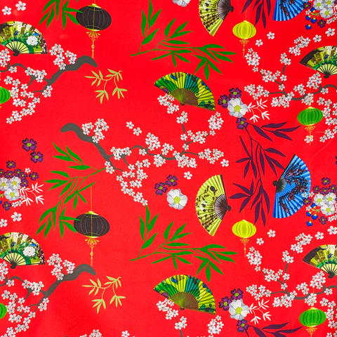Up close polyester silk fabric with black, yellow and green lanterns and multi colour fans surrounded by white cherry blossoms on a bold red background.