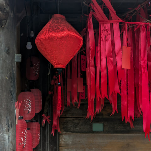 Red silk lantern surrounded by red ribbons and paper lanterns with flowers in Old Town, Hoi An.