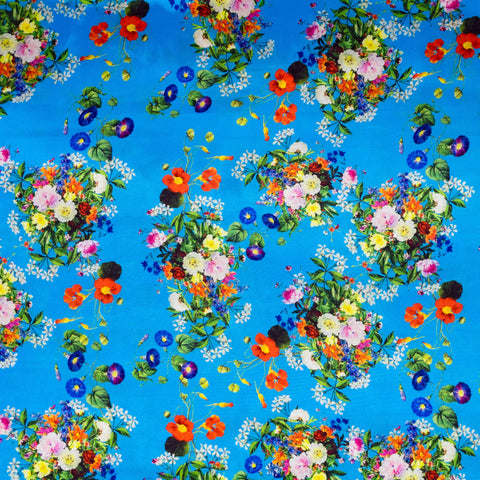 Blue polyester silk fabric with a print of wild flowers in a rainbow of colours.
