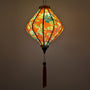 Glowing lozenge shape lantern with yellow floral patterns on red.