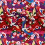 Polyester silk fabric with cranes, their wings gracefully cascading in shades of white, gold, red, and blue. Their backdrop is lush with red and pink flowers, foliage, and dark, majestic purples. 