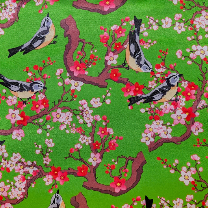 Polyester silk fabric with swallow birds on branches with pink and red blossoms on green background used to create Hoi An Vietnamese lanterns.