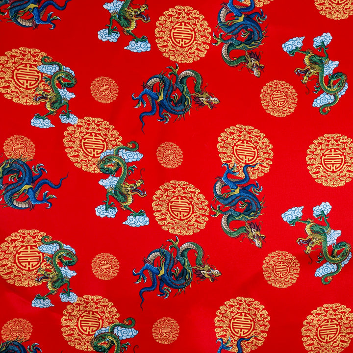 Polyester silk fabric used for creating Hoi An Vietnamese Lanterns featuring green and blue dragons along with golden symbols on striking red background.