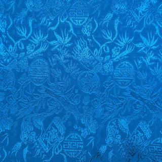 Close up of jacquard silk fabric with intricate patterns of bamboo, lanterns and symbols in blue colour.