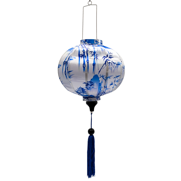 A round Vietnamese silk lantern from Vietnam features a blue print of temples and pagodas high above hilltops with large bamboo trees floating against white background. 
