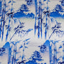 Polyester silk fabric featuring a blue print of temples and pagodas high above hilltops with large bamboo trees floating against white background. 