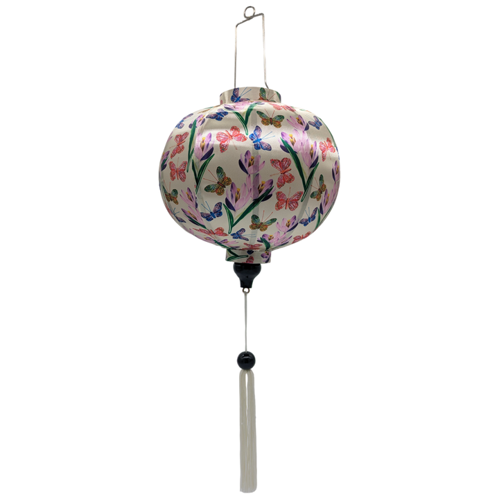 Round shaped lantern with white tassel made with bamboo, steel and a print of stunning print of blue, red and green butterflies fluttering around pink and purple flowers.