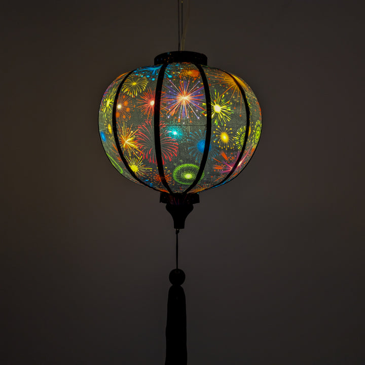 Glowing round lantern with colourful firework design against a black background