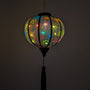 Glowing round lantern with colourful firework design against a black background