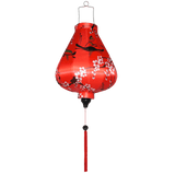 Garlic shaped lantern with red tassel and delicate pink cherry blossoms on red.