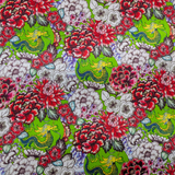 A close up of polyester silk fabric with little green dragons and Chrysanthemums in bloom on a vibrant lime green background.