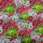 A close up of polyester silk fabric with little green dragons and Chrysanthemums in bloom on a vibrant lime green background.