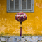 Round shaped lantern hanging in front of a vibrant yellow wall and grey shutters in Old Town with a print featuring colourful patterns and shapes.