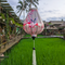 Garlic shaped Vietnamese lantern set against rice fields at Chic Chillax Cafe in Hoi An featuring majestic cranes in vivid reds, hints of teal and delicate blossoms against a calming creamy backdrop. 
