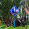 Lozenge shaped lantern with blue tassel hanging outside featuring white cranes flying amidst a dark blue background of geometric shapes, flowers, and golden clouds. 
