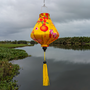 Teardop shaped lantern with yellow tassel and a print of a large orange lantern, firecrackers and pink blossoms on yellow background set against a beautiful river.