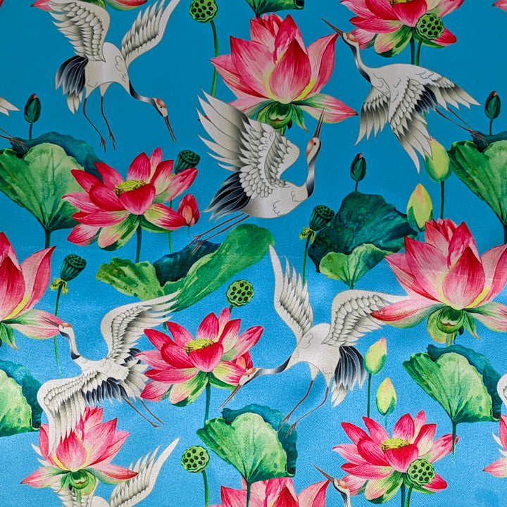 Polyester silk fabric used to created Hoi An Lanterns featuring black-necked cranes in flight and lotus flowers in bloom with large green leaves on a vibrant blue background.