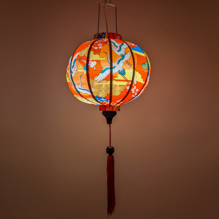 Glowing round silk lantern with cranes in flight with red sun and geometric clouds design on a red background