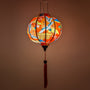 Glowing round silk lantern with cranes in flight with red sun and geometric clouds design on a red background