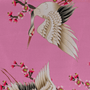 Polyester silk fabric with red-headed white cranes amongst pink cherry blossoms on a pink background.