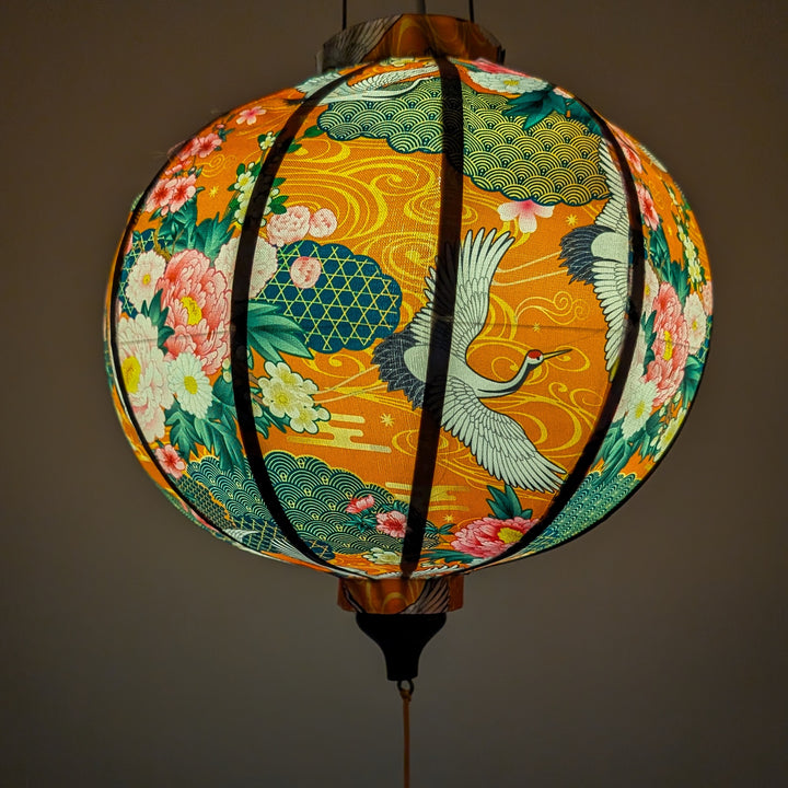 Lantern with floral and crane design creating an orange glow