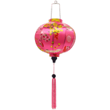 Round shaped Vietnamese lantern with pink tassels featuring a design of cranes, lanterns, firecrackers, and blooms of pink and yellow on a brilliant pink background. 