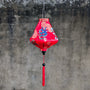 Red Vietnamese silk lantern with dragon design on a textured grey background