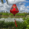 Teardrop shaped lantern with red tassel featuring a print of green and blue dragons along with golden symbols on red silk hanging outside in front of the Thu Bon River.