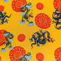 Polyester silk fabric with green and blue dragons and orange symbols on bright yellow used for creating Vietnamese silk lanterns in Hoi An, Vietnam.
