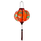 Glowing Round Vietnamese lantern with red tassel with black, yellow and green lanterns and multi colour fans surrounded by white cherry blossoms on a bold red background.