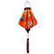 Glowing Teardrop shaped Vietnamese lantern with red tassel and design of yellow fans, a house overlooking trees beneath snow capped mountains and surrounded by blooms of pink on a brilliant red background. 