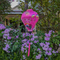 Balloon shaped Vietnamese lantern with pink tassel and a print of yellow fans, a house overlooking trees beneath snow capped mountains and surrounded by blooms of pink hanging in front of a typical Vietnamese house. Perfect for garden decor, special celebrations or to give as a special gift.