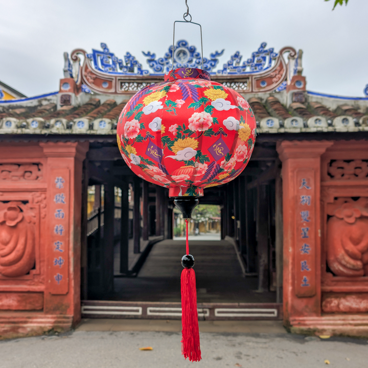Vietnamese silk red lantern with floral patterns hanging in front of the Japanese Bridge entrance in Hoi An.