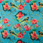 Polyester silk fabric with finches perched in a hibiscus tree filled with pink and peach colour flowers in bloom on blue background used to create Hoi An Vietnamese silk lanterns.