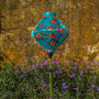 Lozenge shaped lantern hanging in Old Town, Hoi An with a yellow wall and purple flowers in the background.