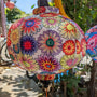 Close up of a round Vietnamese silk lantern with an exquisite illustration of floating flowers on a serene white background, adorned with a burst of enchanting colours like soft pink, tranquil blue, and radiant yellow. 