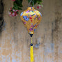 Balloon shape Vietnamese silk lantern with yellow tassel featuring cranes holding flowers and lanterns. Hanging in a tree filled with flowers in Old Town.