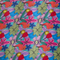 Up close of polyester silk fabric with a print of vibrant and modern floral design with bold, shapes on a blue background. 