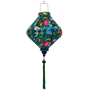 Lozenge shaped lantern with green tassel featuring a print of lush, tropical-inspired design with birds and flowers on a deep green silk fabric.