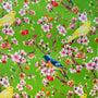 A vibrant fabric design featuring a lush green background with delicate cherry blossoms in full bloom. The branches are adorned with clusters of pink and white flowers, along with small red and orange cherries. Among the blossoms, bright yellow canaries and striking blue and orange flycatchers are perched.