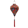 Balloon shaped Vietnamese lantern with red tassel with red, blue, orange, green and yellow paisley print.
