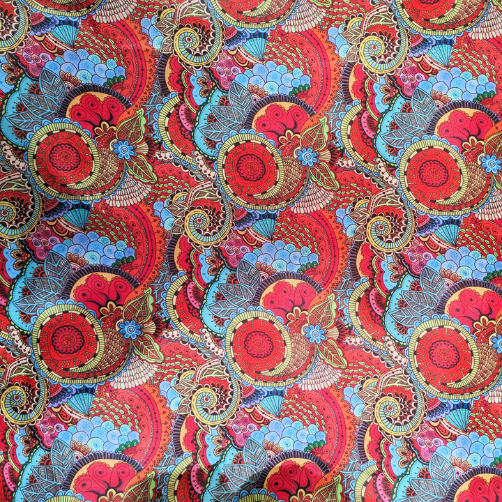 Close up of polyester silk fabric with red, blue, orange, green and yellow paisley print.
