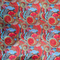 Close up of polyester silk fabric with red, blue, orange, green and yellow paisley print.