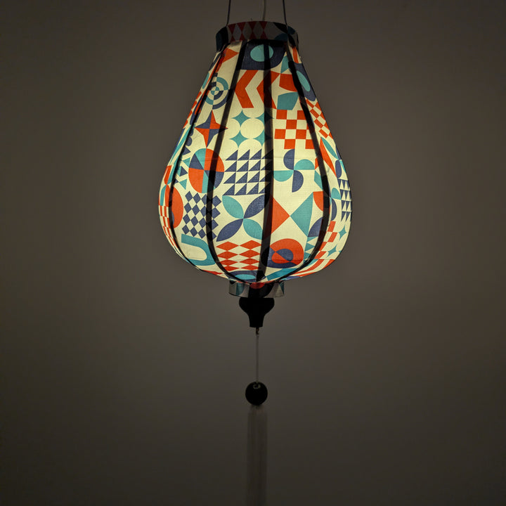 Glowing silk lantern with geometric pattern on a white background with white matching tassel.