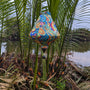 Teardrop shape Vietnamese silk lantern featuring a stunning paisley print with red, greens, blues and yellows hanging in front of a river in Cam Thanh.