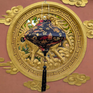 A black lantern with gold dragon illustrations and red accents hangs in front of a large ornate gold dragon on a terracotta-coloured wall.