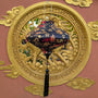 A black lantern with gold dragon illustrations and red accents hangs in front of a large ornate gold dragon on a terracotta-coloured wall.