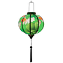 Glowing handcrafted Hoi An lantern with goldfish and floral design on green fabric, traditional Vietnamese home decor.